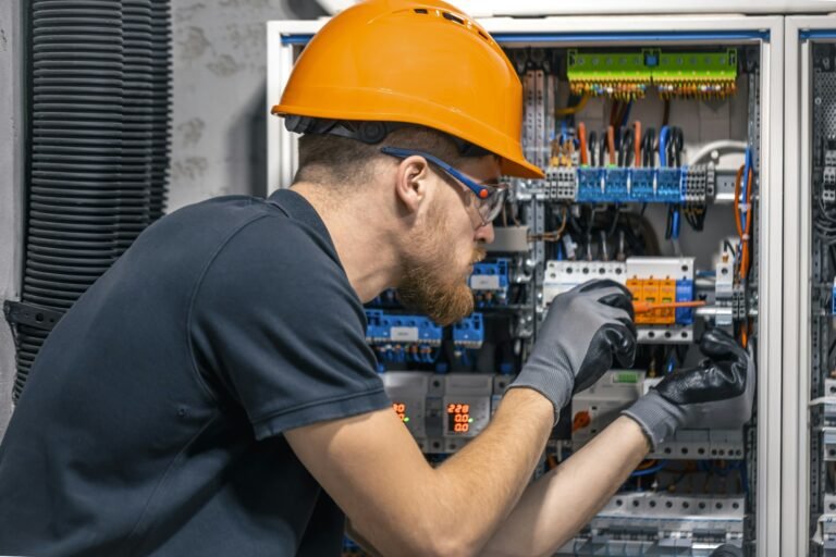 Male electrician working in a switchboard with fuses.