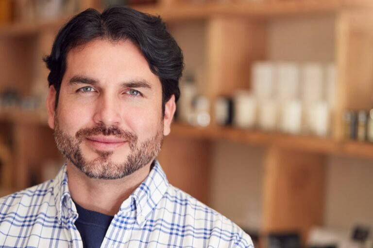Portrait Of Male Owner Of Gift Store Standing In Front Of Shelves With Cosmetics And Candles